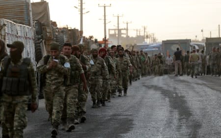 Turkey-backed Syrian rebel fighters walk together in the border town of Akcakale in Sanliurfa province