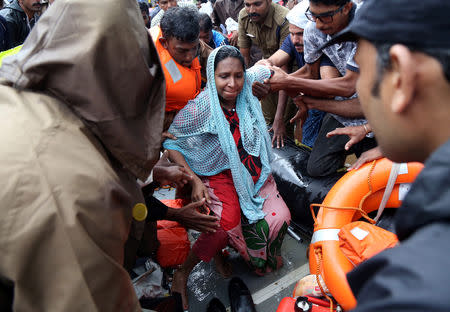 Rescuers help a pregnant woman to disembark a boat after she was evacuated from a flooded area in Aluva in Kerala, India, August 18, 2018. REUTERS/Sivaram V