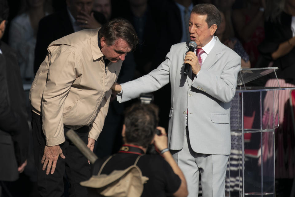 Brazil's President Jair Bolsonaro takes a bow next to televangelist R.R. Soares, at an International Grace of God Church event, at Botafogo beach in Rio de Janeiro, Brazil, Saturday, Feb. 15, 2020. Tens of thousands of people gathered to celebrated the 40th anniversary of the evangelical church. (AP Photo/Leo Correa)