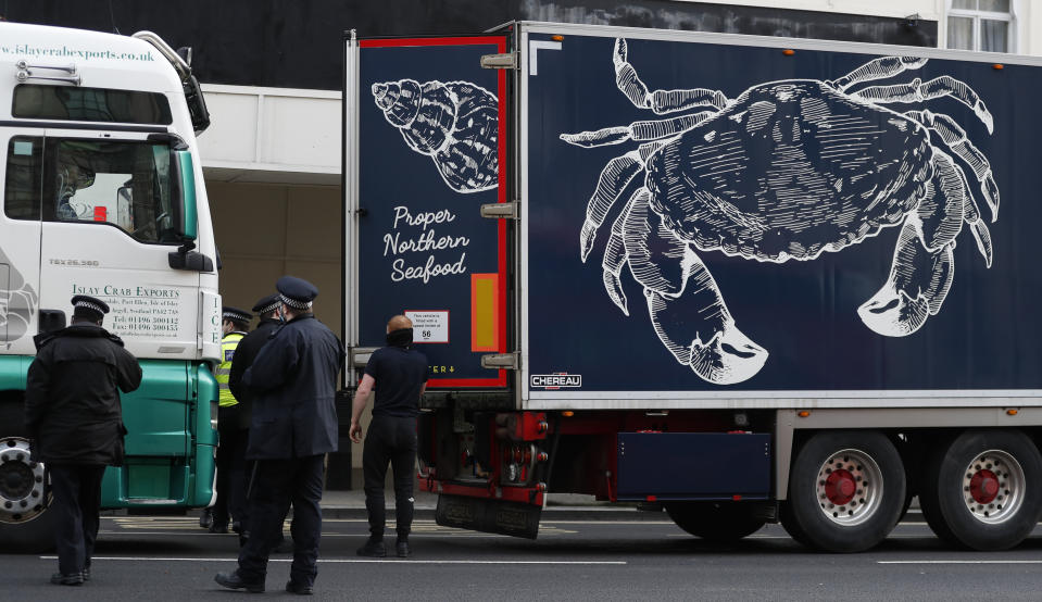 Police speak to shellfish export truck drivers as they are stopped for an unnecessary journey in London, Monday, Jan. 18, 2021, during a demonstration by British Shellfish exporters to protest Brexit-related red tape they claim is suffocating their business. The drivers were later stopped by police and issued with fines for an 'unnecessary journey' due to the national lockdown to curb the spread of the coronavirus. (AP Photo/Alastair Grant)