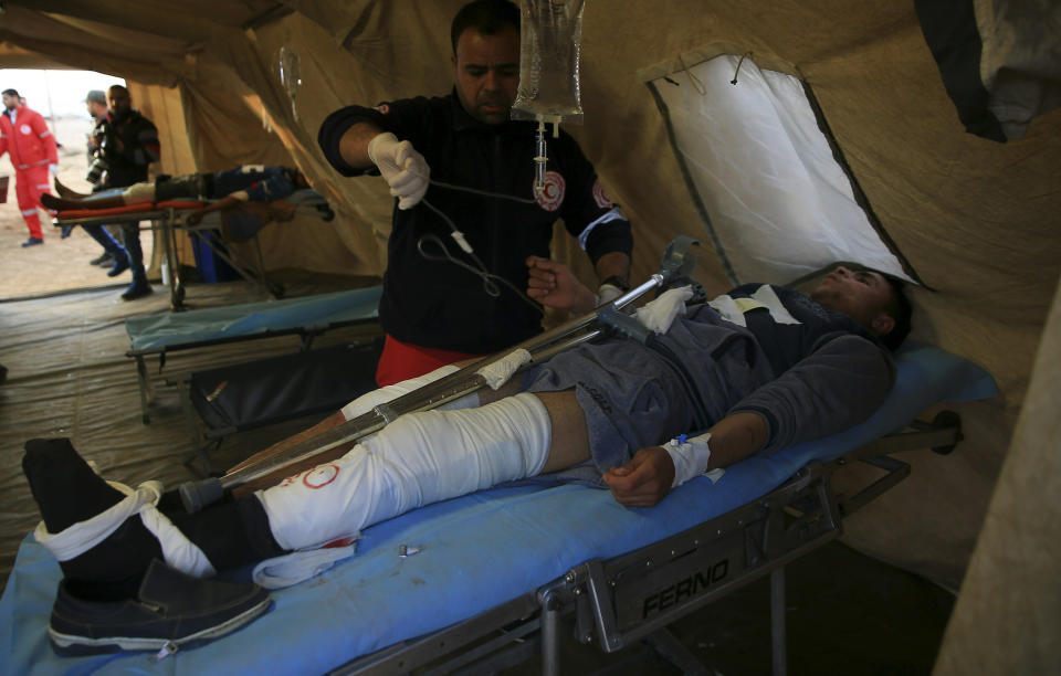 Medics treat a wounded youth protester in a field clinic tent after he was shot during a protest near the fence of the Gaza Strip border with Israel, near Beit Lahiya, northern Gaza Strip, Tuesday, Feb. 19, 2019. (AP Photo/Adel Hana)