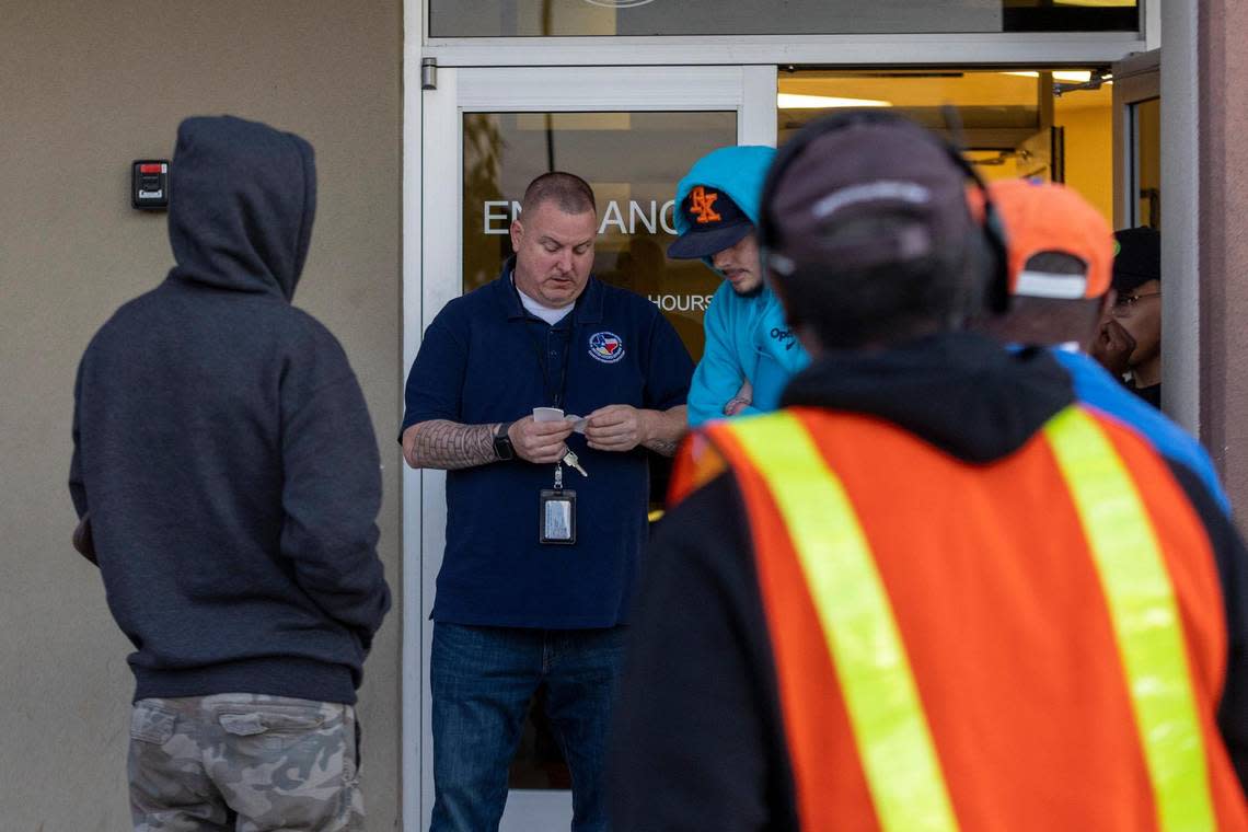 An employee distributes tickets to people who have been in line for hours waiting for a walk-in appointment at the Texas Department of Public Safety Driver License Mega Center in Fort Worth on Tuesday, Oct. 18, 2022. With residents waiting up to months for a scheduled appointment, some people choose to arrive early and spend their morning waiting for a walk-in.