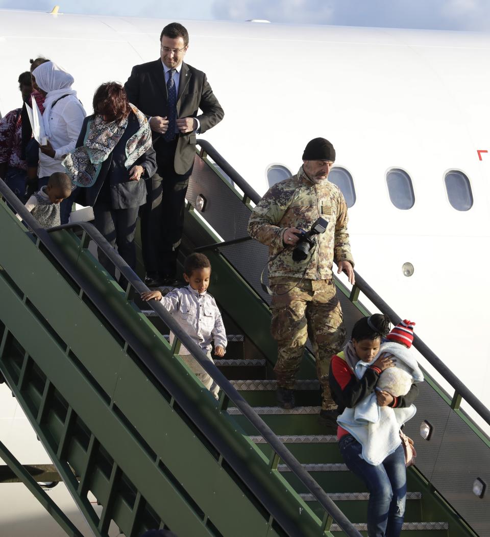 Italian Interior Ministry Undersecretary Stefano Candiani, top, adjusts his jacket as he stands on the steps while asylum seekers disembark from an Italian military aircraft which arrived from Misrata, Libya, at Pratica di Mare military airport, near Rome, Monday, April 29, 2019. Italy organized a humanitarian evacuation airlift for a group of 147 asylum seekers from Ethiopia, Eritrea, Somalia, Sudan and Syria. (AP Photo/Andrew Medichini)