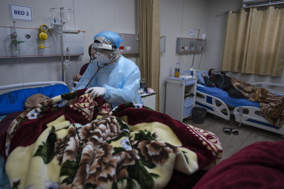 A medical staffer attends a Palestinian patient infected with COVID-19, at the coronavirus ward inside the Palestinian Medical Complex, in the West Bank city of Ramallah, Thursday, Feb. 3, 2022. Palestinians are facing a winter coronavirus surge driven by the omicron variant, placing stress on the medical system even though vaccines are widely available. (AP Photo/Nasser Nasser)