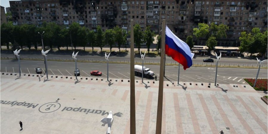 Russian invaders hang a Russian flag over Freedom Square in occupied Mariupol