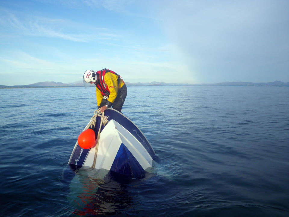 Second place photo by volunteer crew member Paul Collins shows a RNLI volunteer on an upturned boat in Abersoch, Wales. Three people had to jump overboard after their powerboat took on water. When the crew arrived, just two feet of the boat was left above the surface (Paul Collins/Rex Features)