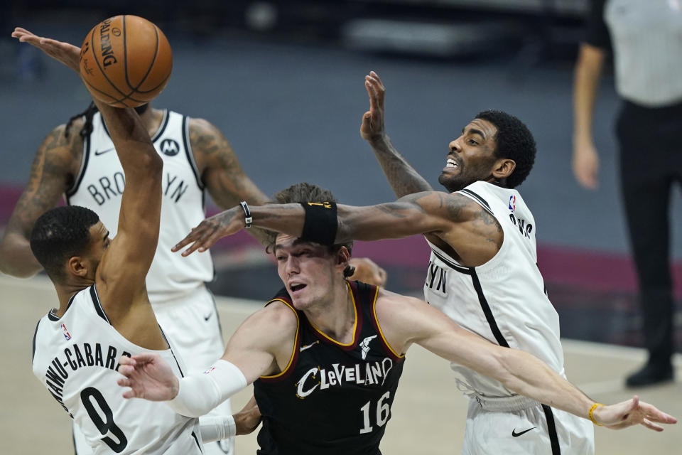 Brooklyn Nets' Kyrie Irving, right, knocks the ball loose from Cleveland Cavaliers' Cedi Osman, center, as Timothe Luwawu-Cabarrot tries to catch it during the first half of an NBA basketball game, Wednesday, Jan. 20, 2021, in Cleveland. (AP Photo/Tony Dejak)
