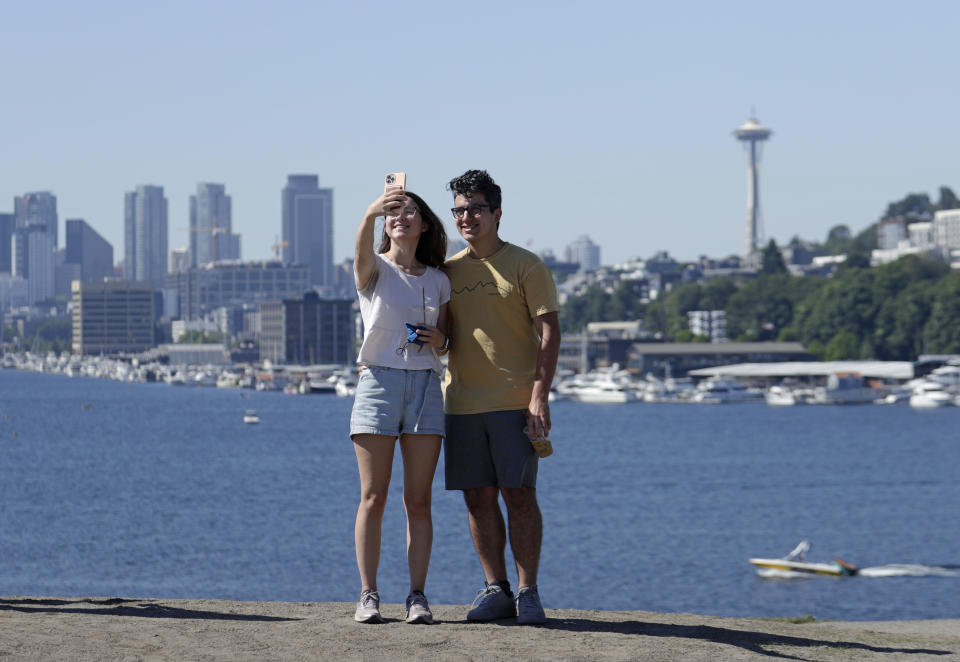 Zach Kamran and Anna Denson take selfies from the top of a hill at Gas Works Park in the morning during a heat wave hitting the Pacific Northwest, Sunday, June 27, 2021, in Seattle. Yesterday set a record high for the day with more record highs expected today and Monday. Kamran said they will likely spend the rest of the day inside as the heat rises. (AP Photo/John Froschauer)