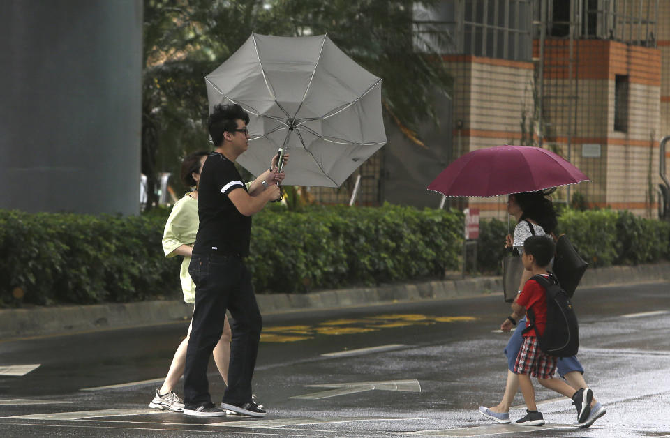 People cross a street in powerful gusts of wind generated by typhoon Ineng in Taipei, Taiwan, Saturday, Aug. 24, 2019. (AP Photo/Chiang Ying-ying)