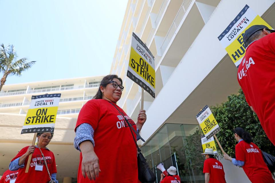 Hotel workers wearing red shirts and carrying picket signs