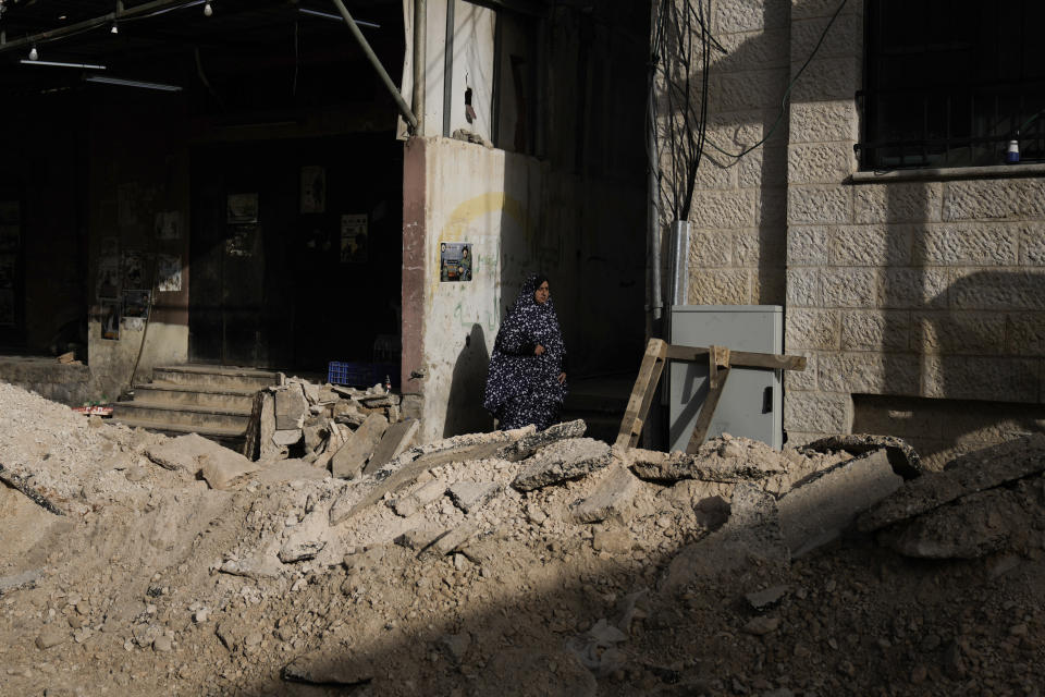 Palestinians walk by a damaged road following an Israeli army operation in Jenin refugee camp, West Bank, Sunday, Nov. 26, 2023. Israeli forces operating in the occupied West Bank killed at least eight Palestinians in a 24-hour period, Palestinian health officials said Sunday. (AP Photo/Majdi Mohammed)