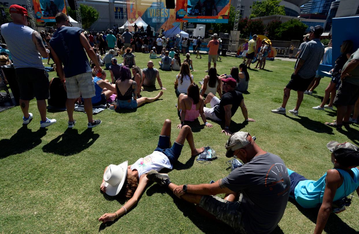 Sofia Marsala uses her cowboy hat to shield her face from the sun while she listen to Tyler Booth perform at the Vibes Stage during the CMA Fest on Thursday, June 9, 2022, in Nashville, Tenn. 