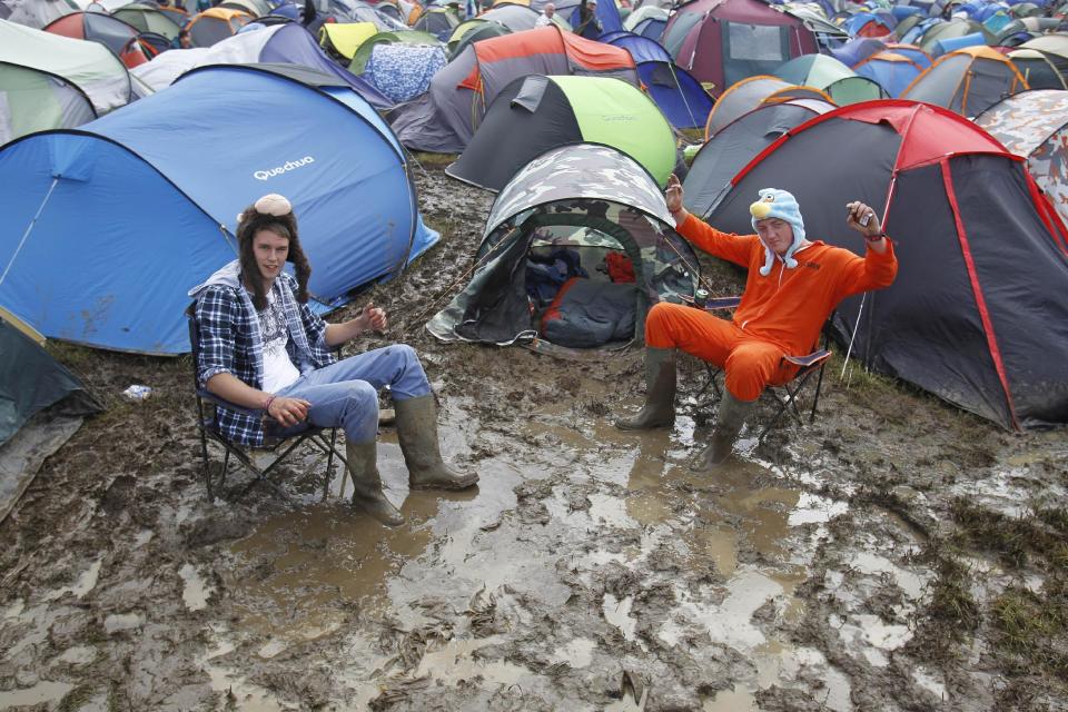 Festival goers sits amongst the mud at the campsite at the Isle of Wight festival on the Isle of Wight england Friday June 22, 2012. Hundreds of music fans have been stranded in their cars overnight after rainstorms caused chaos on travel routes to the Isle of Wight Festival. (AP Photo/Peter Byrne/PA) UNITED KINGDOM OUT