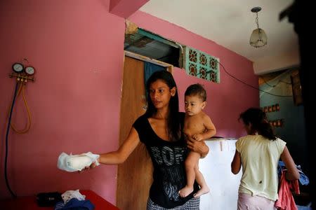 Geraldine Rocca, 29, carries her son Jeremy, ahead of her sterilization surgery in Caracas, Venezuela July 20, 2016. REUTERS/Carlos Garcia Rawlins