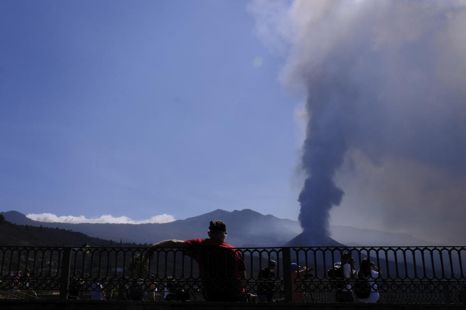 A man looks towards a volcano as it continues to erupt in El Paso on the canary island of La Palma, Spain, Saturday Oct. 9, 2021. A new lava flow has belched out from the La Palma volcano and it threatens to spread more destruction on the Atlantic Ocean island where molten rock streams have already engulfed over 1,000 buildings. The partial collapse of the volcanic cone overnight sent a new lava stream Saturday heading toward the western shore of the island. (AP Photo/Daniel Roca)