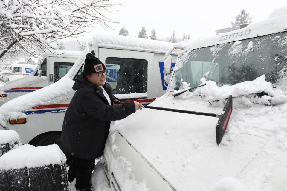 Mail carrier Kirsten Toner scraps the snow of her delivery truck as he preps to make her deliveries on Friday, March 1, 2024, in Truckee, Calif. The most powerful Pacific storm of the season is forecast to bring up to 10 feet of snow into the Sierra Nevada by the weekend (AP Photo/Andy Barron)