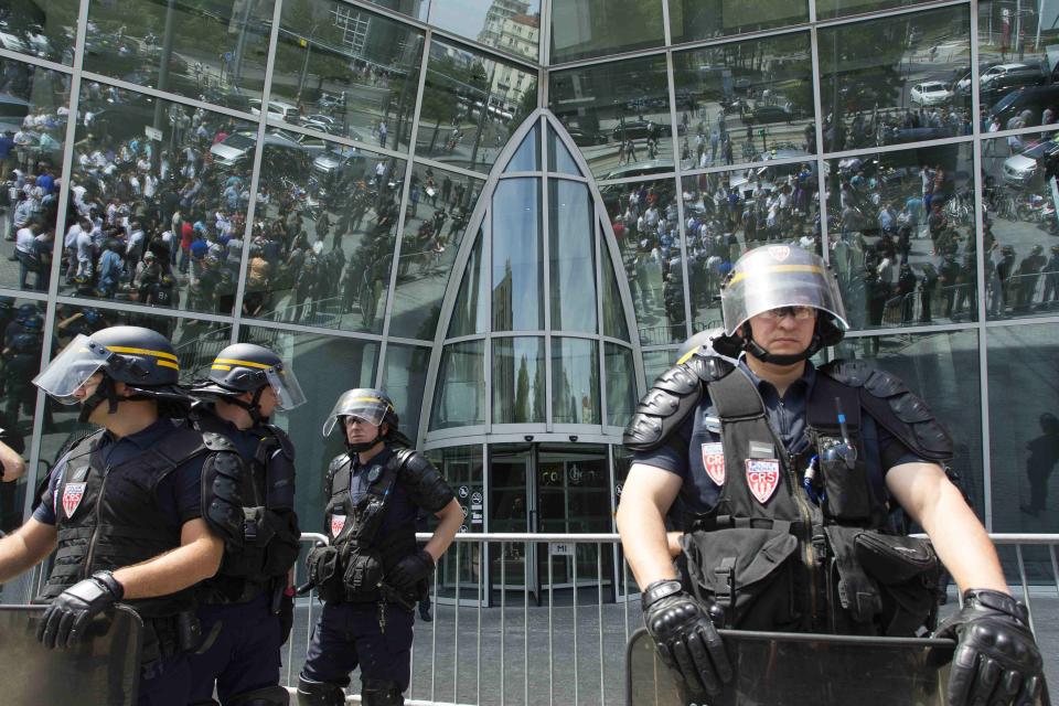 French riot police stand in front of the Tour Oxygene as taxi drivers attend a demonstration during a national protest against car-sharing service Uber, in Lyon, France, June 25, 2015. (REUTERS/Emmanuel Foudrot)