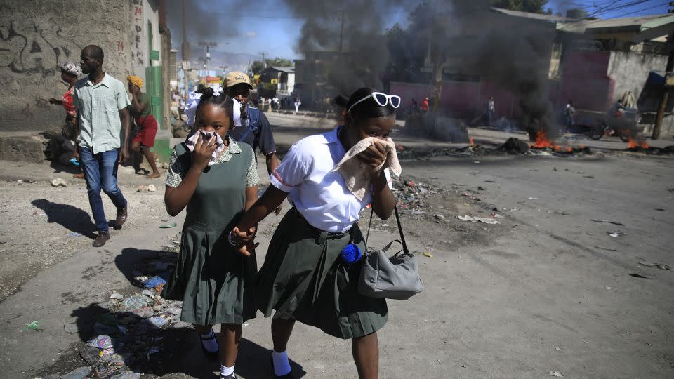 Students walk past a burning barricade set up by members of the police protesting bad police governance in the Haitian capital Port-au-Prince in January. - Odelyn Joseph/AP