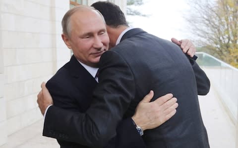 Russia's President Vladimir Putin (L) welcomes Syria's President Bashar al-Assad during a meeting at Bocharov Ruchei residence.  - Credit: Photo by Mikhail Klimentyev\\TASS via Getty Images