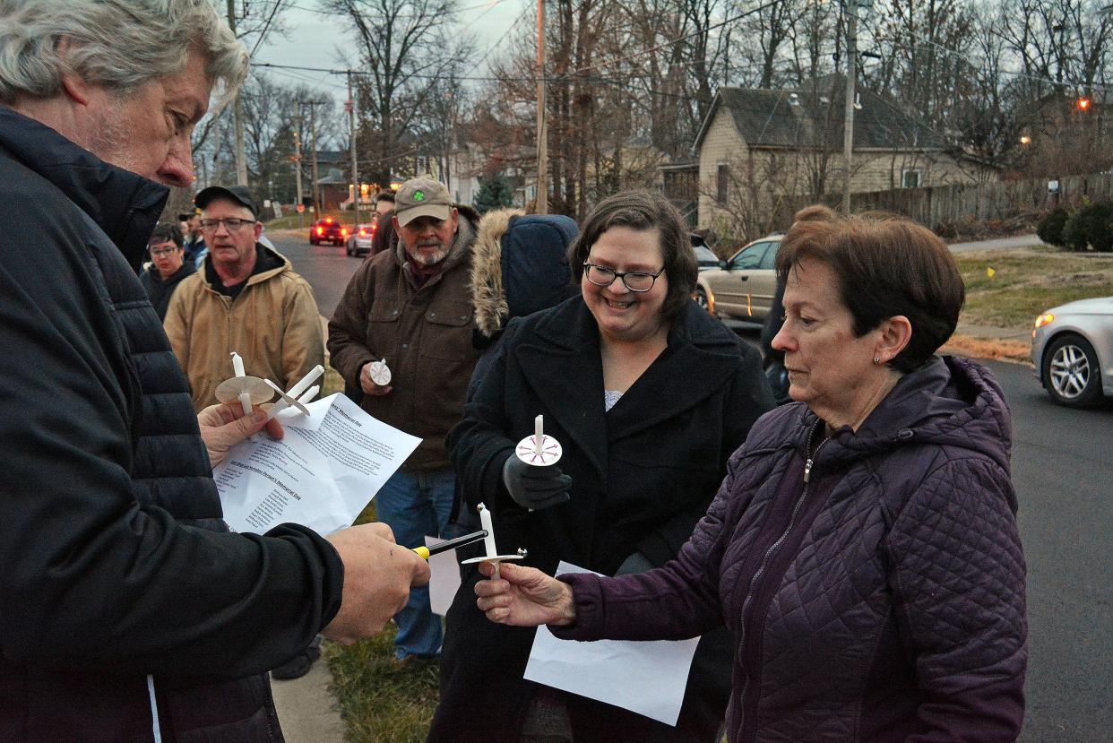 Gary Busiek with the Columbia Salvation Army works to light candles Thursday held by Amelia Lewis and Jean Gruenewald at the Salvation Army Harbor House before a memorial service starts for the city's unsheltered residents who died in 2023.