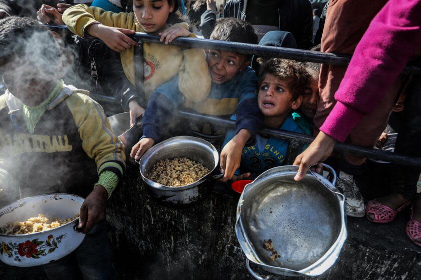 RAFAH, GAZA - FEBRUARY 09: Palestinians children wait in line to receive food prepared by volunteers for Palestinian families ,displaced to Southern Gaza due to Israeli attacks, between rubbles of destroyed buildings in Rafah, Gaza on February 09, 2024. In the Gaza, where Israeli attacks persist, Palestinians are grappling with food shortages. The city of Rafah, which has become a refuge for tens of thousands displaced due to the Israeli attacks, is facing increasing challenges in sourcing food. (Photo by Abed Rahim Khatib/Anadolu via Getty Images)