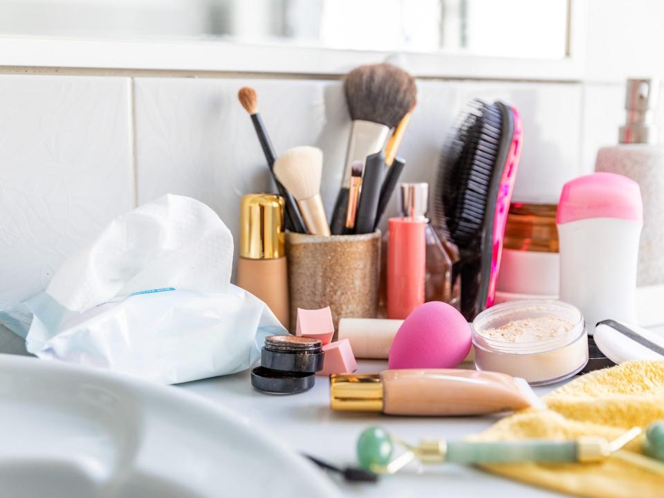 A bathroom counter with makeup products on it.