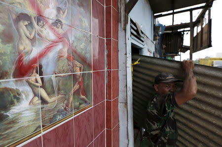 A man removes corrugated iron from a dwelling (unseen) before it is demolished in the Kalijodo red-light district in Jakarta, Indonesia February 26, 2016 REUTERS/Darren Whiteside