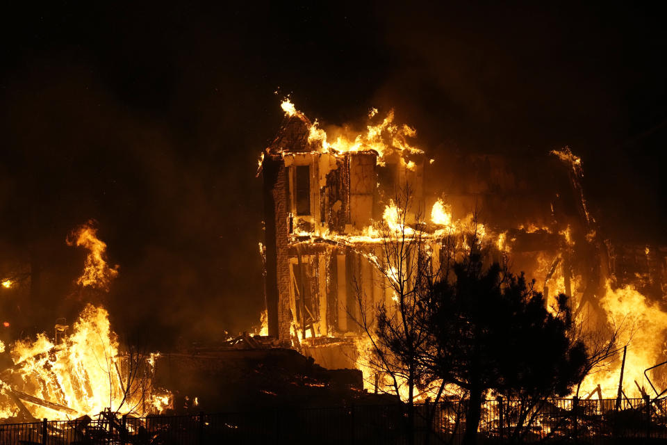 FILE - Homes burn as a wildfire rips through a development near Rock Creek Village, Dec. 30, 2021, near Broomfield, Colo. In Colorado and other states hit by natural disasters this year, the pandemic has injected extra uncertainty and created more obstacles for families trying to rebuild. (AP Photo/David Zalubowski, File)