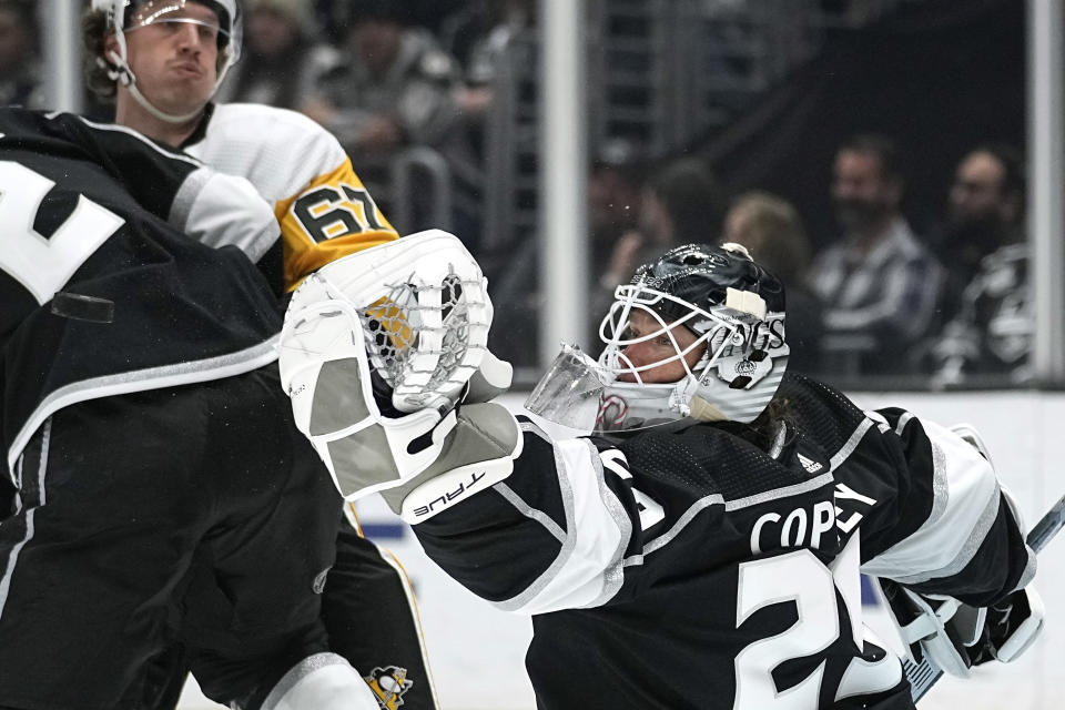 Los Angeles Kings goaltender Pheonix Copley, right, makes a glove save as Pittsburgh Penguins right wing Rickard Rakell watches during the second period of an NHL hockey game Saturday, Feb. 11, 2023, in Los Angeles. (AP Photo/Mark J. Terrill)