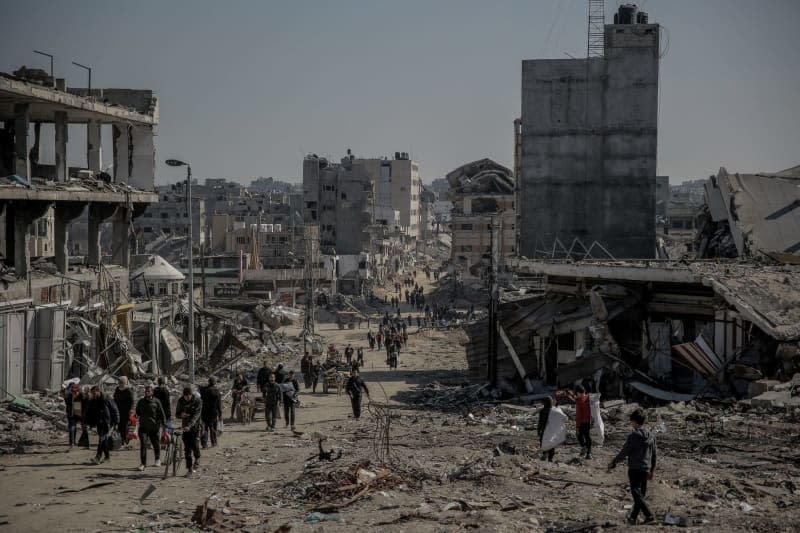 Palestinians walk next to damaged buildings on their way back to their homes in the wake of the Israeli army withdrew from North of Gaza Strip. Omar Ishaq/dpa