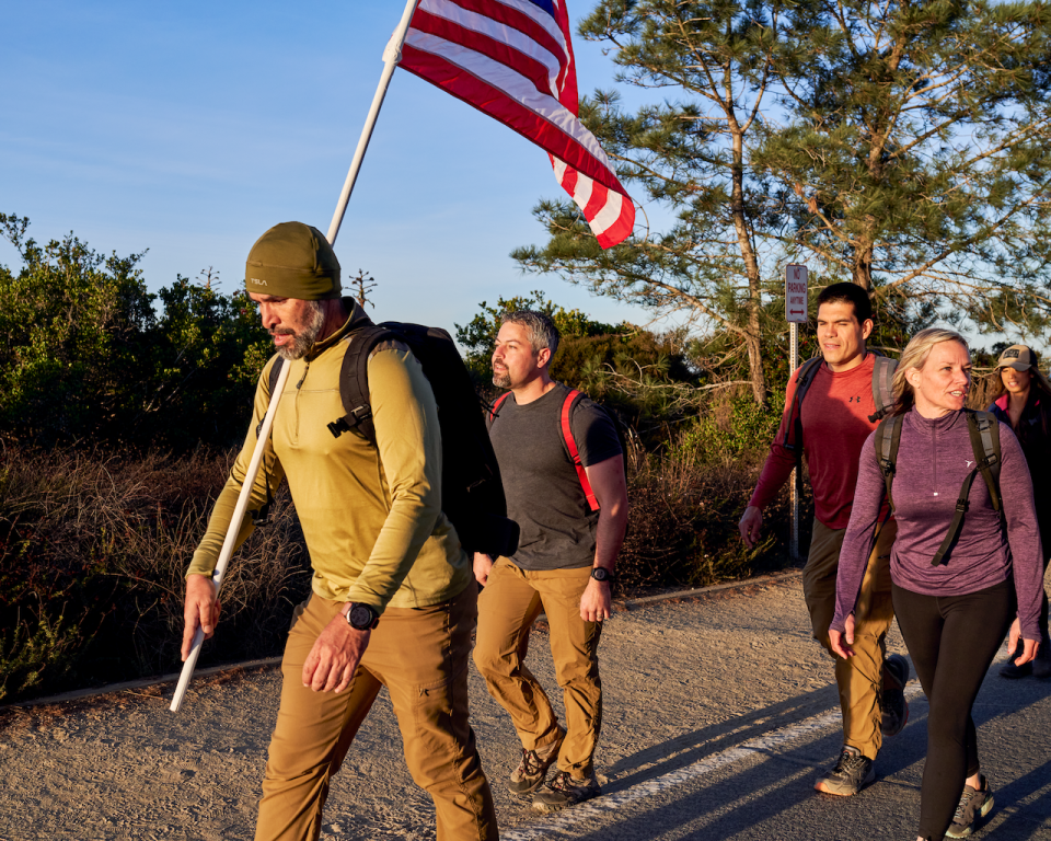 a group of people walking on a path with a flag