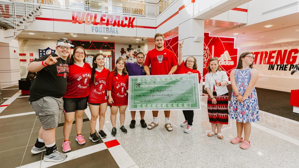 Joe Shimko (center) presents a $30,000 check to GiGi's Playhouse Raleigh