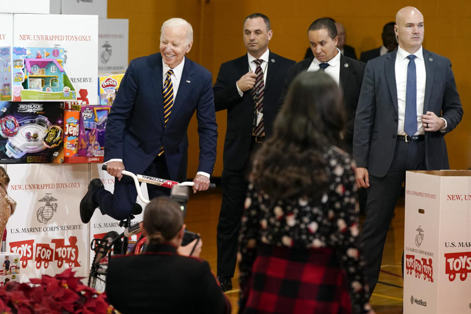 President Joe Biden pretends to ride a bike during a Toys for Tots sorting event at Joint Base Myer-Henderson Hall in Arlington, Va., Monday, Dec. 12, 2022. (AP Photo/Patrick Semansky)