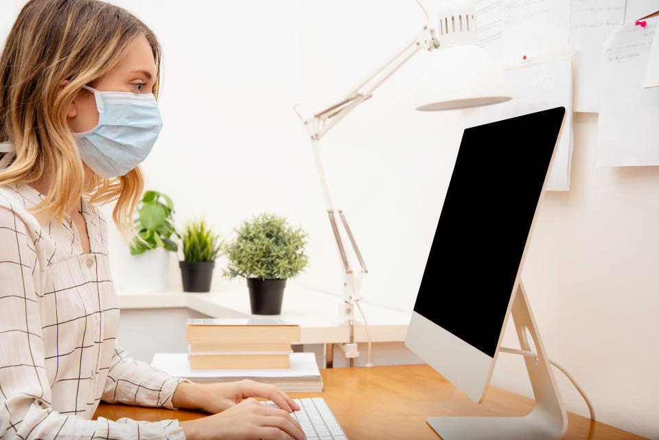 Young business woman working from home wearing protective mask