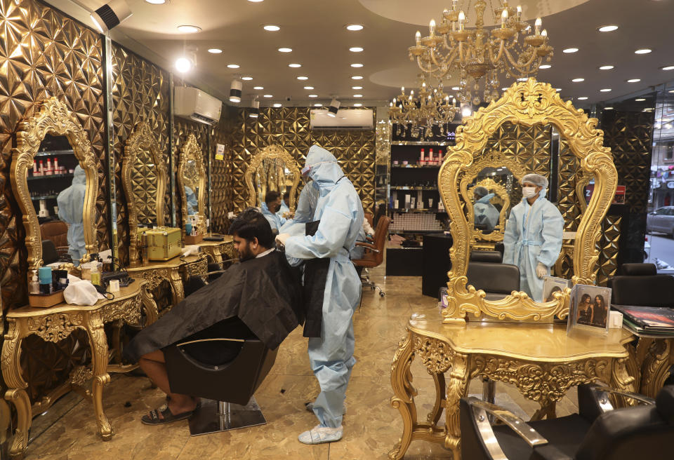 A hairdresser in personal protective suit attends to a customer at a hair salon in New Delhi, India, Friday, June 5, 2020. Businesses and shops reopened in many states as a three-phase plan to lift the nationwide coronavirus lockdown began despite an upward trend in new infections. Indian Prime Minister Narendra Modi’s government has stressed that restrictions are being eased to focus on promoting economic activity, which has been severely hit by the lockdown. (AP Photo/Manish Swarup)