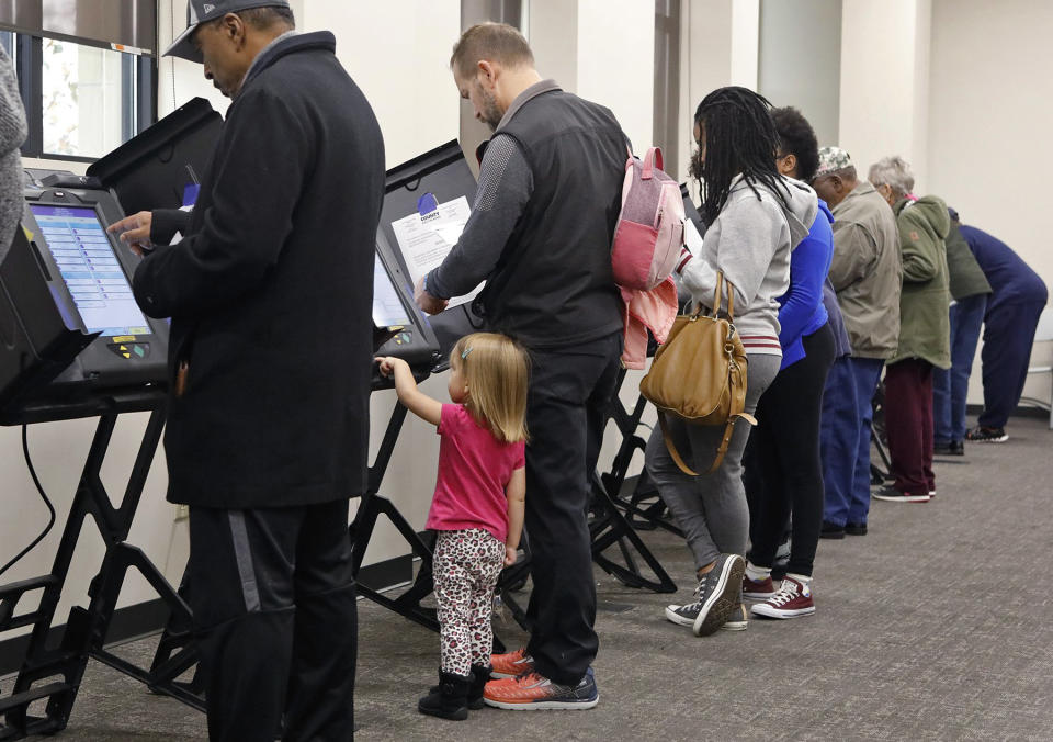 Madelyn Whitehead, 2, helps her father, Rob Whitehead, from Maryland Heights, vote during absentee voting on Monday, Nov. 5, 2018, at the St. Louis County Board of Elections in St. Ann, Mo. (J.B. Forbes/St. Louis Post-Dispatch via AP)