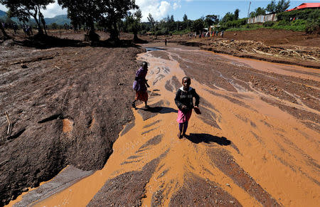 Children walk in muddy waters after a dam burst, which unleashed water at nearby homes, in Solio town near Nakuru, Kenya May 10, 2018. REUTERS/Thomas Mukoya