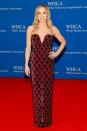 <p>wears a heavily embellished column gown with a v-neckline and front slit. </p>