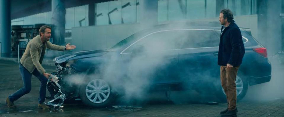 Adult Adam and Louis standing next to a wrecked Subaru in "The Adam Project"