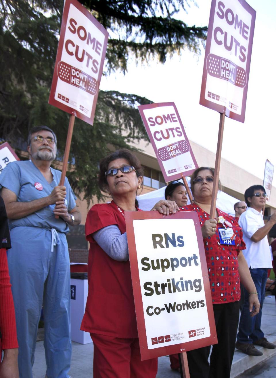 FILE -- In this Sept. 21, 2011 file photo, Kaiser Medical assistants Darlene De LaTorra, left, Latisha Tucker, Registered Nurse Edith Fernandez, center, joins more than 200 other health care workers and their supporters in a demonstration outside the Kaiser in Sacramento, Calif. If approved by voters in November, Proposition 32 would prohibit corporations and unions, like the California Nurses Association, from collecting money for state political activities from employees or members through paycheck deductions. It also prohibits unions and corporations from making donations to state candidates.(AP Photo/Rich Pedroncelli,File)