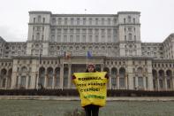 A Greenpeace activist holds a banner in the yard of Romania's Parliament, during a protest against a Canadian company's plan to set up Europe's biggest open-cast gold mine in Romania, in Bucharest December 9, 2013 A special Romanian parliament commission overwhelmingly rejected a draft bill that would have allowed Canada's Gabriel Resources to set up Europe's biggest open-cast gold mine in the small Carpathian town of Rosia Montana last month. However, parliament plans to revise a mining law that could open way for the project. REUTERS/Bogdan Cristel (ROMANIA - Tags: ENVIRONMENT SOCIETY CIVIL UNREST POLITICS BUSINESS)