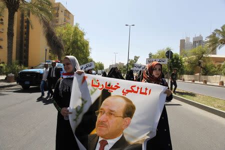 Iraqis carry portraits of incumbent Iraqi Prime Minister Nuri al-Maliki as they gather in support of him in Baghdad August 13, 2014. REUTERS/Ahmed Saad