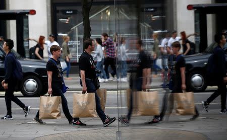 Shoppers are reflected in a window as they walk along Oxford Street in London, Britain July 9, 2016. Picture taken July 9, 2016. REUTERS/Peter Nicholls