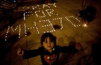 Una niña malasia reacciona ante la cámara mientras otra persona enciende velas en una vigilia por los pasajeros del vuelo MH370 de Malaysia Airlines desaparecido en pleno vuelo en la plaza de la Independencia en Kuala Lumpur, el 10 de marzo de 2014 ( | Manan Vatsyayana)