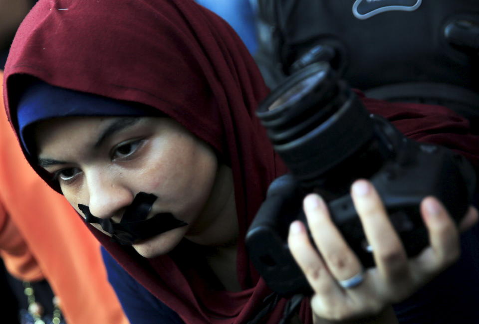 A news photographer with her mouth taped holds up her camera during a protest against the detention of Ahmed Ramadan, a photojournalist with Egyptian private newspaper "Tahrir," in front of the Syndicate of Journalists in Cairo, Egypt on Aug. 17, 2015.