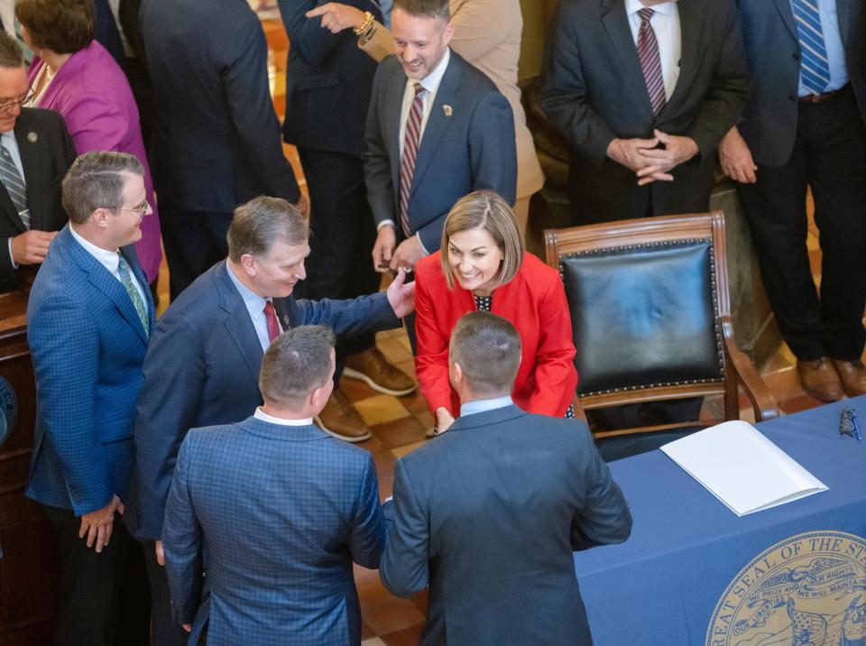 Governor Kim Reynolds hands out pens after signing a sweeping property tax cut bill that will rein in local governments' revenue growth and provide new tax breaks for military veterans and seniors, Thursday, May 4, 2023.