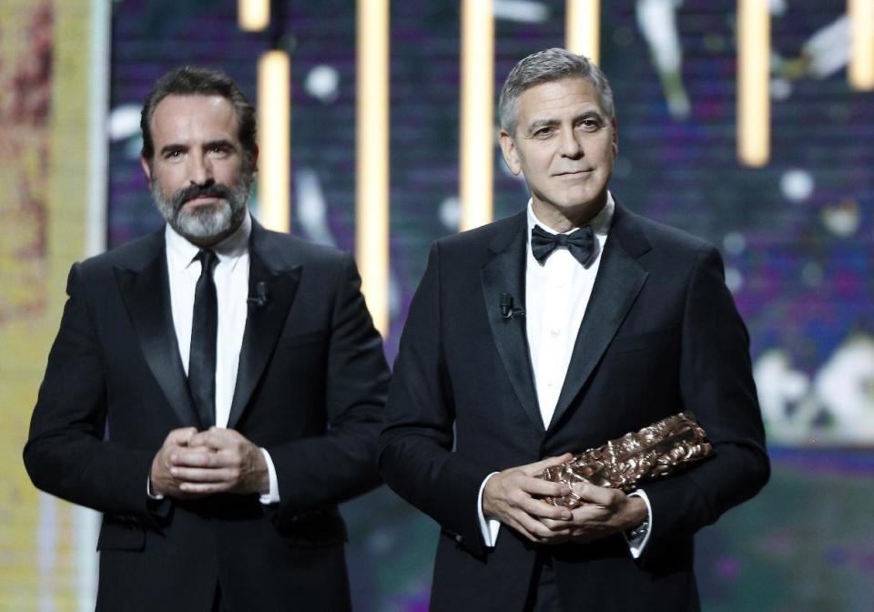 Actor George Clooney, right, reacts on stage after he received an Honorary Cesar award by French actor Jean Dujardin during the 42nd Cesar Film Awards ceremony at Salle Pleyel in Paris, Friday, Feb. 24, 2017. This annual ceremony is presented by the French Academy of Cinema Arts and Techniques. (AP Photo/Thibault Camus)