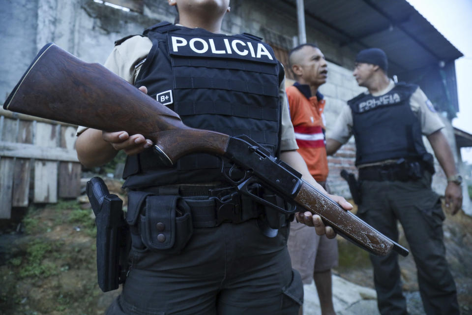 Una policía hace guardia mientras un hombre es detenido en un operativo para buscar armas y drogas con el fin de combatir a grupos criminales y extorsionadores, el jueves 4 de abril de 2024, en el barrio de Nueva Guayaquil, en Guayaquil, Ecuador. (AP Foto/César Muñoz)