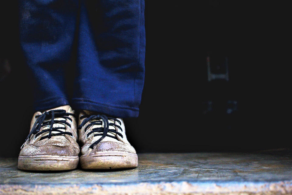 Carlos, de 8 años, juega en su casa con los zapatos blancos deteriorados. Para<span class="s1"> ir a la escuela -que queda a más de 15 kilómetros de su casa- se pone otros que también están desgastados: el que corresponde a su pie derecho tiene un hueco por el que se le sale el dedo gordo</span>