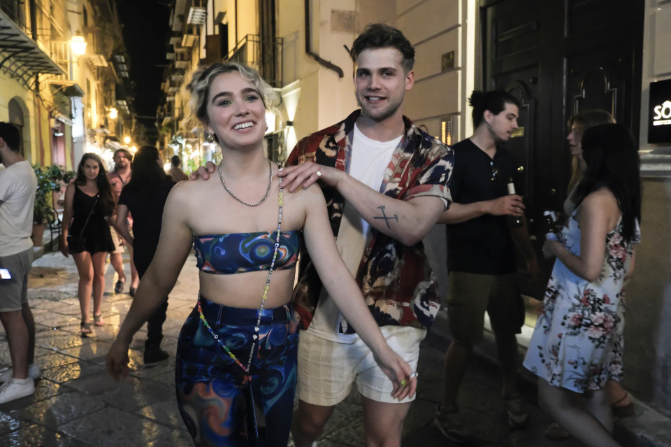 Saoirse Ronan marche avec Jack Lowden, qui a la main sur son épaule, dans une rue animée avec des gens en arrière-plan.  Ronan porte un crop top à motifs et un pantalon